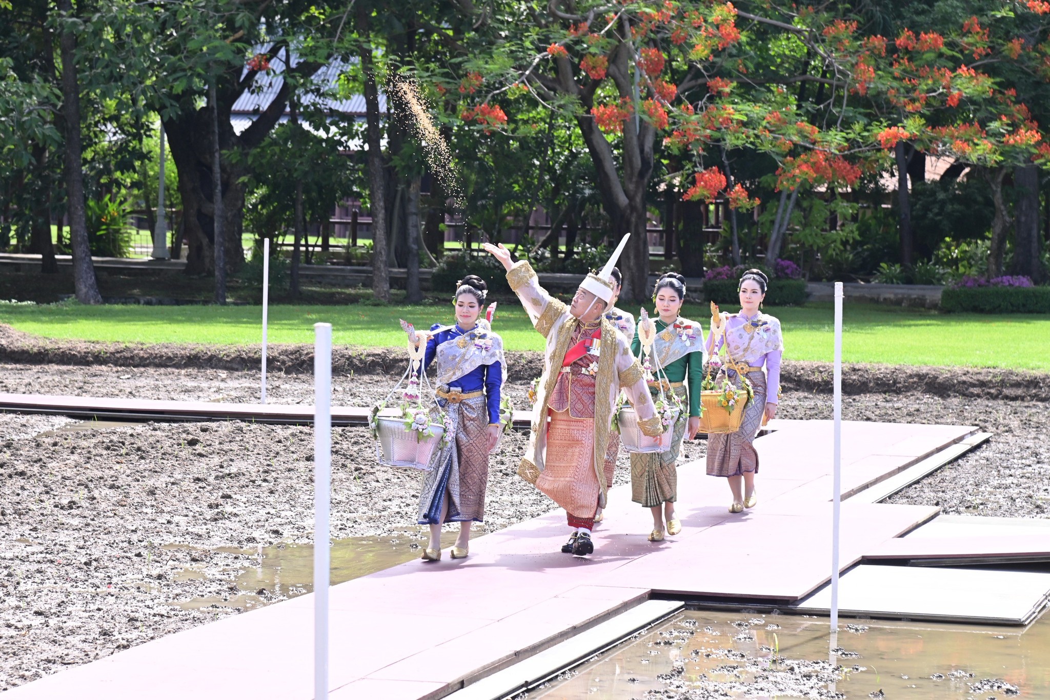 title - ปลัดเกษตรฯ ผู้ทำหน้าที่พระยาแรกนา พร้อมด้วยเทพีคู่หาบทอง และเทพีคู่หาบเงิน ประกอบพิธีหว่านเมล็ดพันธุ์ข้าวในแปลงนาทดลอง